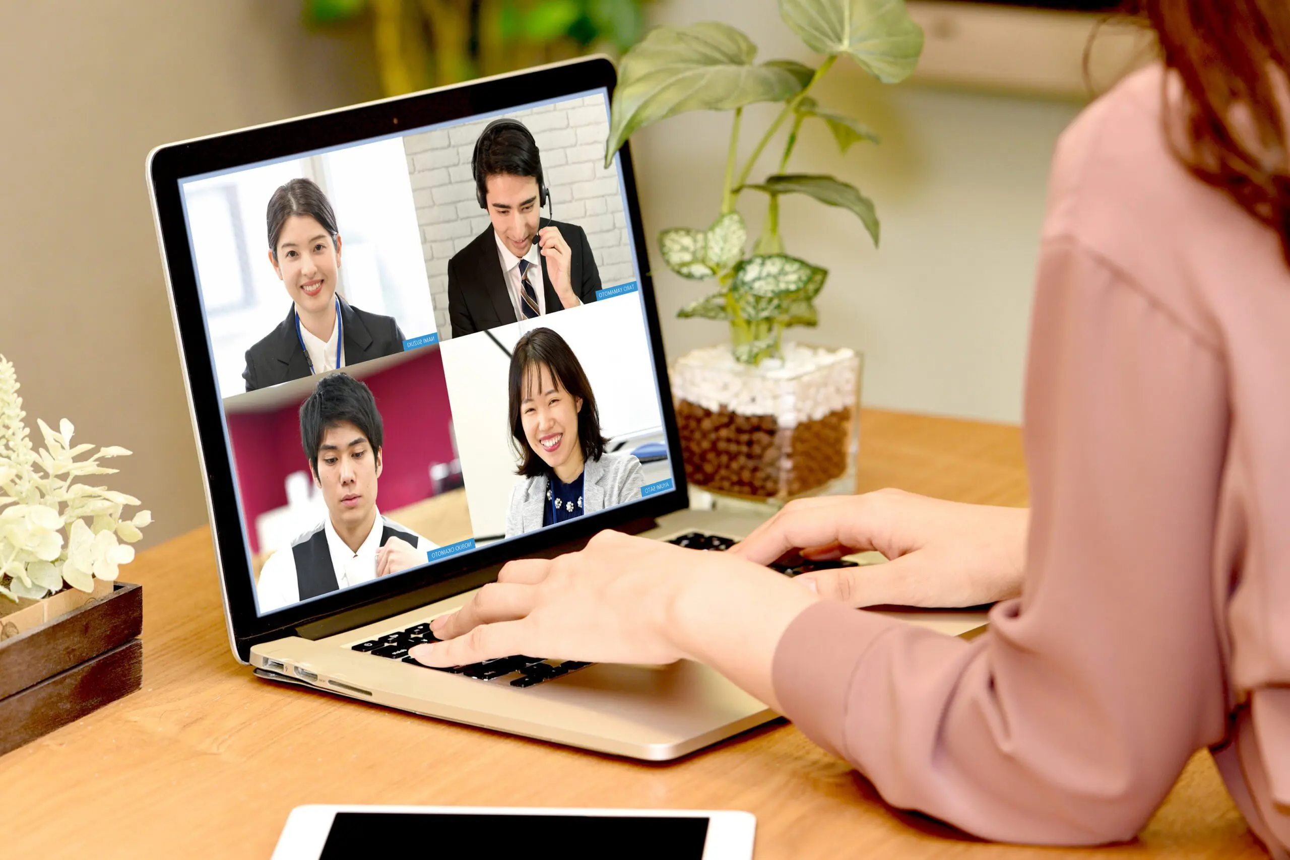 2023 年 4 月版のリモートワークのトレンドでは、ある人がラップトップ画面で他の 4 人とビデオ会議に参加しています。彼らはタブレットと鉢植えが飾られた木製の机に座り、おそらくエンジニア転職の機会に向けたポイントについて話し合っているでしょう。.